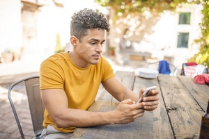 Man with a taper fade and curly hair playing on his phone